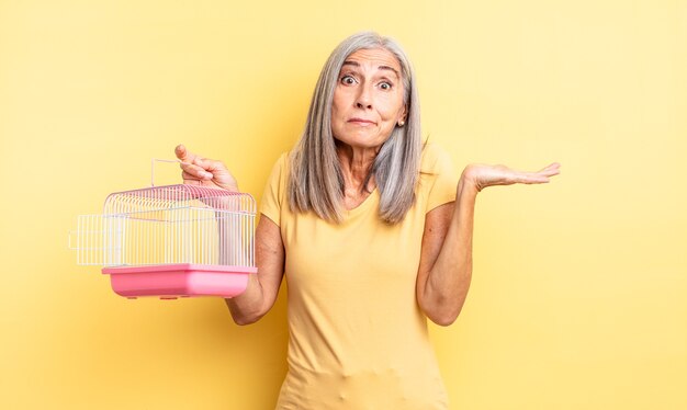 Mooie vrouw van middelbare leeftijd die zich verward en verward voelt en twijfelt. huisdierenkooi of gevangenisconcept