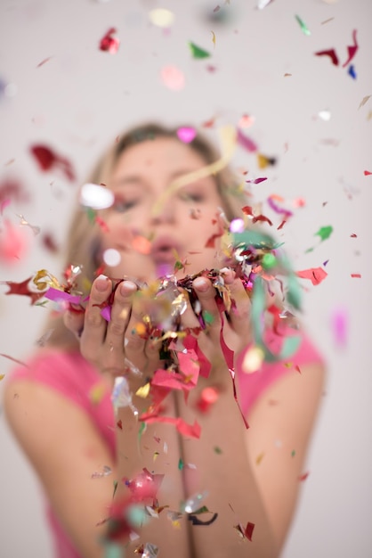 Mooie vrouw waait confetti in de lucht partij oudejaarsavond viering geïsoleerd op witte achtergrond