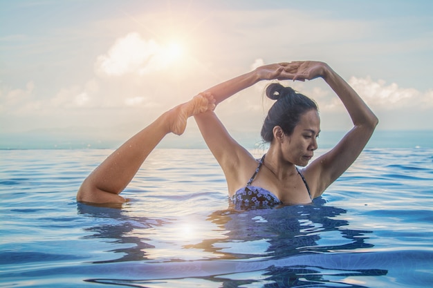 Mooie vrouw yoga in turkoois blauw zwembad.