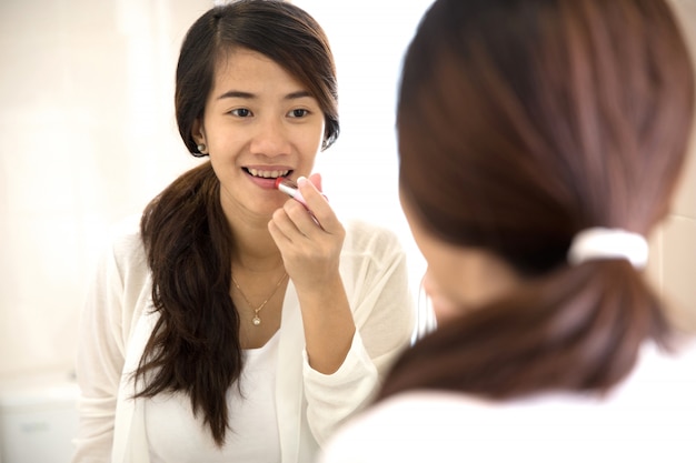 Mooie vrouw zetten make-up op, het aanbrengen van lippenstift op haar lippen