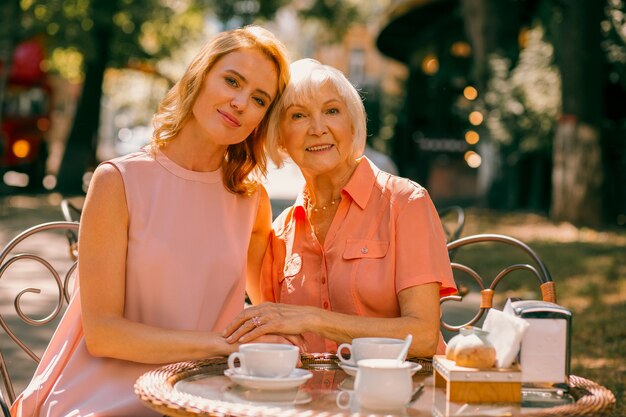 Mooie vrouw zit met haar bejaarde moeder hoofd aan kop aan de cafétafel