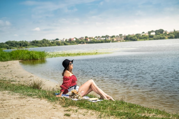 Mooie vrouw zit om te ontspannen in de buurt van de vijver in het park Genieten van de natuur buiten zomerdag