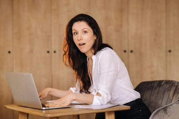 Mooie vrouw zit op kantoor en werkt op een laptop