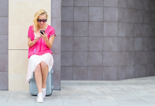 Mooie vrouw zitten op de koffer kijken naar de telefoon