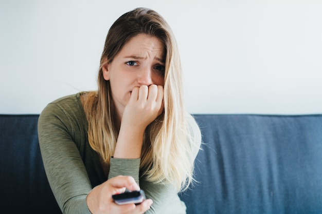 Mooie vrouw zittend op een bank en tv kijken