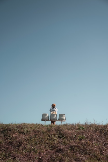 Mooie vrouw zittend op een stoel en het nemen van een foto op heuvel met blauwe lucht