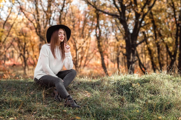 Mooie vrouw zittend op het gras op zonnige herfstdag