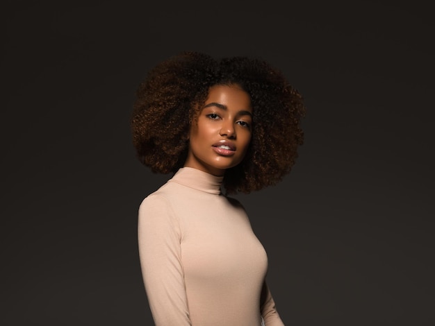 Mooie vrouw zwarte huid mooie Afro-Amerikaanse mooi model in trui op zwarte achtergrond.