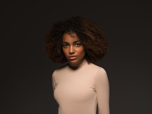 Mooie vrouw zwarte huid mooie Afro-Amerikaanse mooi model in trui op zwarte achtergrond.