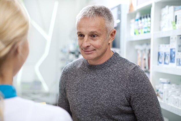 Mooie vrouwelijke apotheker die haar cliënt helpt