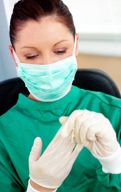 Mooie vrouwelijke arts met scrubs afstappen van haar handschoenen