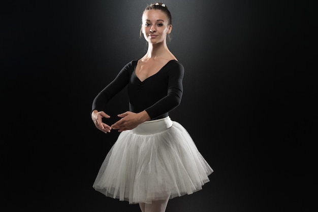 Mooie vrouwelijke balletdanser op een zwarte achtergrond Ballerina draagt een tutu en pointe-schoenen