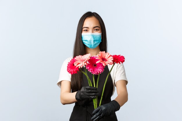 Mooie vrouwelijke barista in een zwarte schort met gezichtsmasker