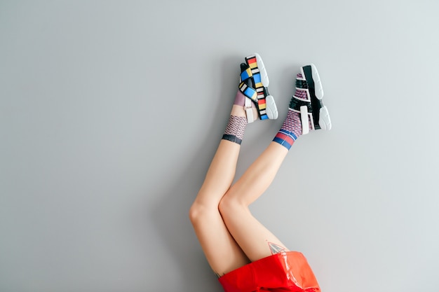 Mooie vrouwelijke benen in kleurrijke niet-overeenkomende sokken en sandalen