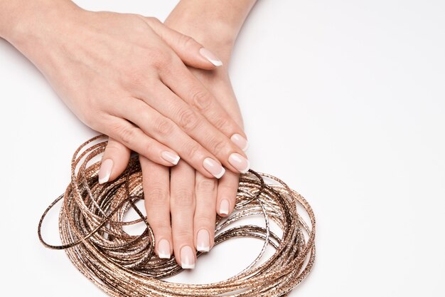 Mooie vrouwelijke goed verzorgde handen met Franse manicure met ketting over lichte ondergrond