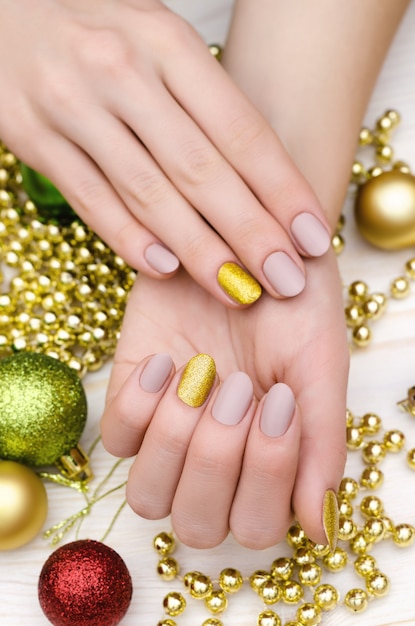 Mooie vrouwelijke hand met beige nagelontwerp. Kerst manicure.