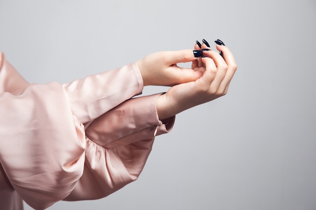 Mooie vrouwelijke hand met manicure nagels geïsoleerd op een grijze achtergrond