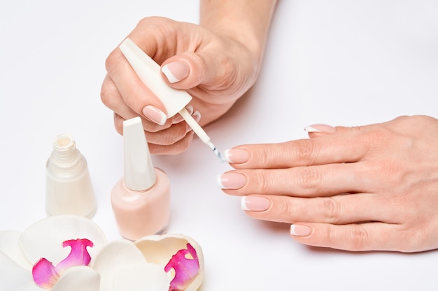 Mooie vrouwelijke handen met Franse manicure over lichtgrijs oppervlak