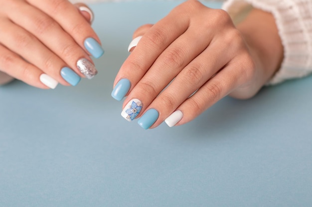 Mooie vrouwelijke handen met romantische manicure nagels blauwe en witte gellak