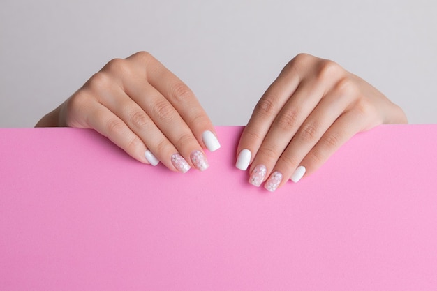 Mooie vrouwelijke handen met roze en witte manicure nagels bloemontwerp