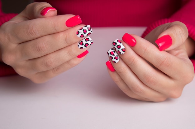 Mooie vrouwelijke handen met roze manicure nagels luipaard print ontwerp op witte achtergrond