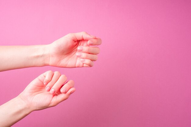 Mooie vrouwelijke handen met verse schattige manicure, huid en nagel zorg concept, roze achtergrond