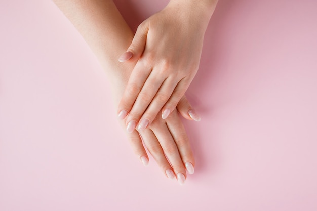Mooie vrouwelijke handen op een roze achtergrond. Spa en lichaamsverzorging concept. Afbeelding voor reclame.