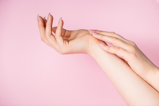 Mooie vrouwelijke handen op een roze achtergrond. Spa en lichaamsverzorging concept. Afbeelding voor reclame.