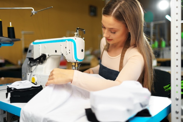 Mooie vrouwelijke naaister werken met stof op haar werkplek in textielfabriek