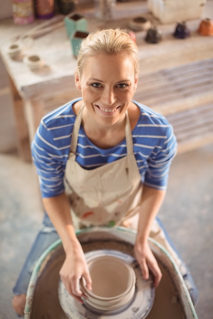 Foto mooie vrouwelijke pottenbakker die pot maakt