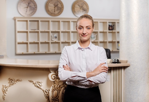 Foto mooie vrouwelijke receptioniste in uniform poseren tegen de lobbybalie van het hotel