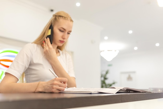 Mooie vrouwelijke receptioniste of secretaresse bij de receptie in een medische kliniek of ziekenhuis Soft focus