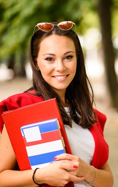 Mooie vrouwelijke student die een boek houdt openlucht