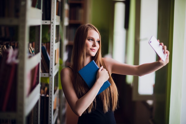 Mooie vrouwelijke student in de universiteitsbibliotheek