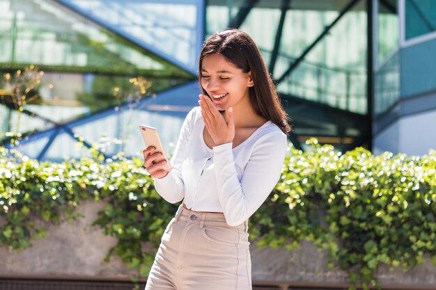 Foto mooie vrouwelijke student video chatten met ouders op de telefoon voor de campus