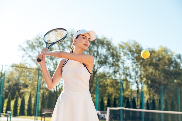 Mooie vrouwelijke tennisspeler die een workout heeft op de tennisbaan