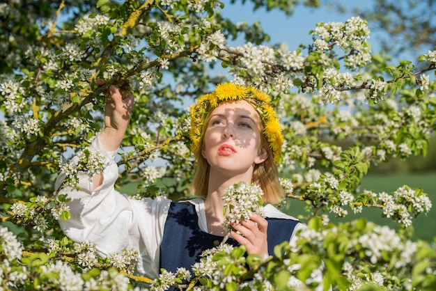 Mooie vrouwelijke vrouw in nationale klederdracht met witte lentebloemen