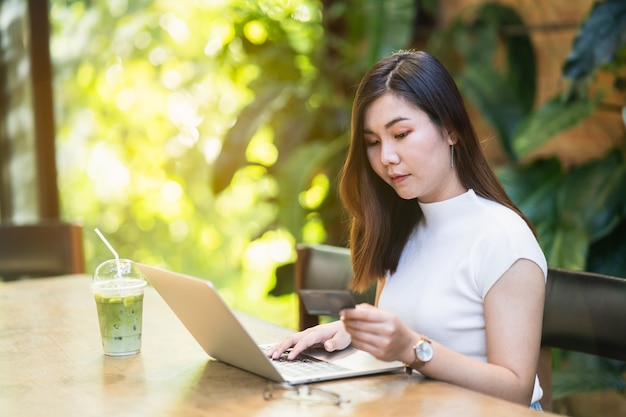 Mooie vrouwen die creditcard en laptop gebruiken om online te winkelen