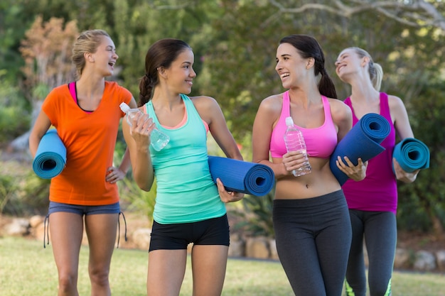 Mooie vrouwen die oefeningsmat in park houden