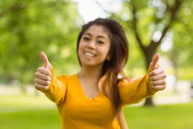 Mooie vrouwen gesturing duimen omhoog in park