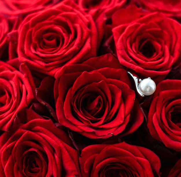 Mooie witgouden parelring en boeket rode rozen luxe sieraden liefdescadeau op Valentijnsdag en romantische feestdagen