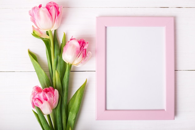 Mooie witte en roze tulpen en fotolijst voor uw tekst op witte houten achtergrond.