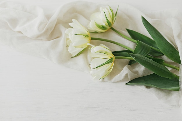 Mooie witte tulpen met zachte stof op rustieke houten tafel met ruimte voor tekst Happy Mothers day Lenteboeket uit de tuin Vrouwendag