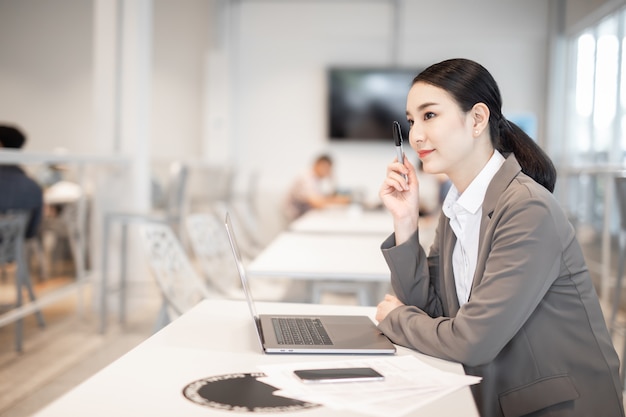 mooie zakelijke Aziatische vrouw met pak werken in bureau met behulp van computer met kopieerruimte