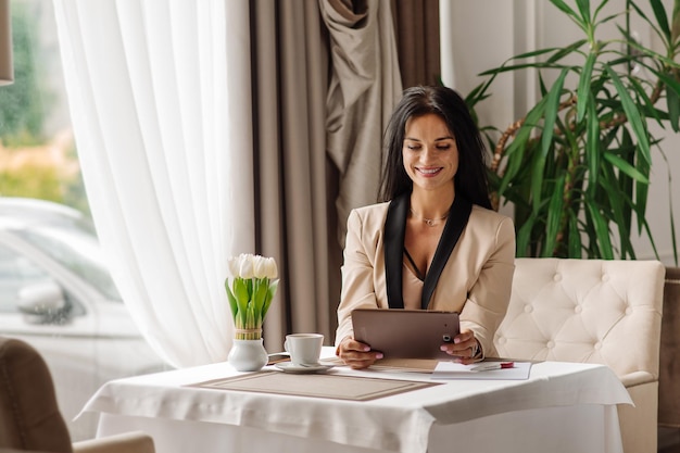 Mooie zakenvrouw die een tablet gebruikt voor werk tijdens de koffiepauze in het café