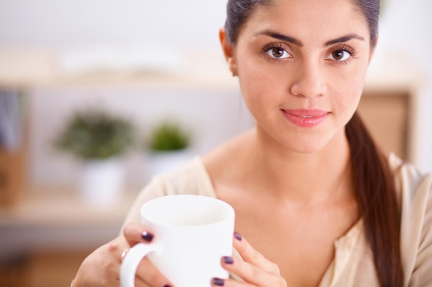 Mooie zakenvrouw die van koffie geniet in een helder kantoor, zittend