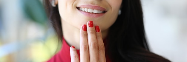 Mooie zakenvrouw glimlach en kin met rode manicure close-up te houden
