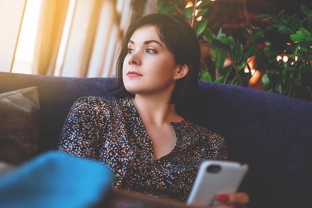 Mooie zakenvrouw in het restaurant belt op je smartphone Schattige brunette in een café