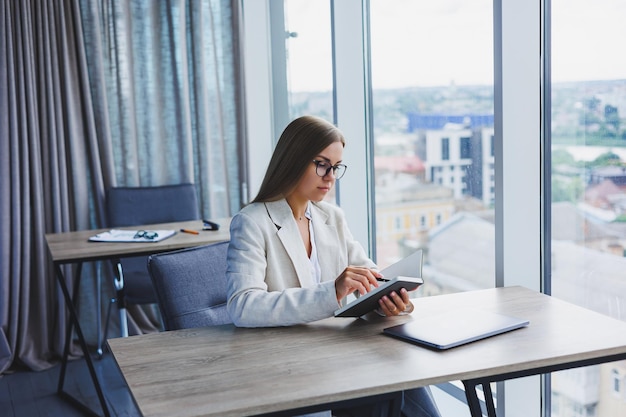 Mooie zakenvrouw kijken door notebook gericht op werk freelancer werk op afstand studeren studie modern kantoor binnen sociale afstand vrouw in kantoor met bril en laptop