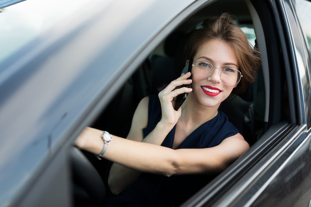 Mooie zakenvrouw met behulp van mobiele telefoon in de auto